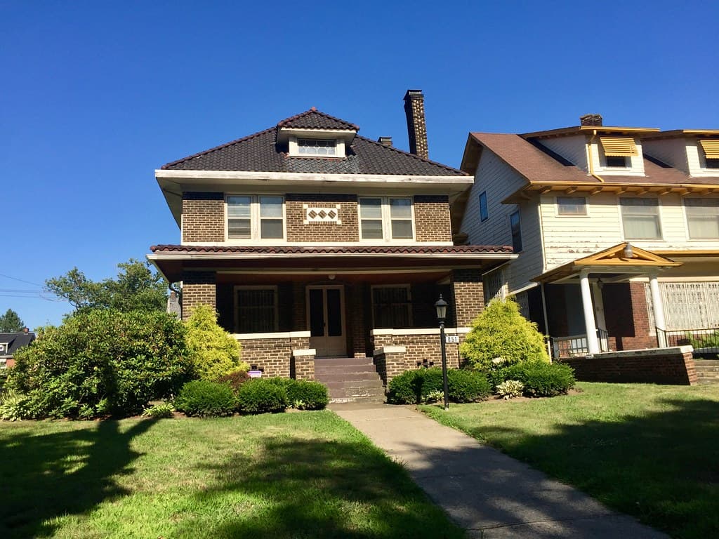 Brick house with a front porch and lawn in Cleveland’s East Boulevard Historic District, Glenville